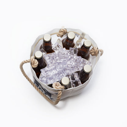 A top-down view shows the Sea Bags US Naval Academy Beverage Bucket, crafted from recycled sail cloth and styled after a classic Midshipmen cooler, holding six brown glass bottles with caps nestled in ice cubes on a white background. by Sea Bags