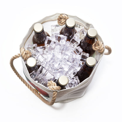 Six brown glass bottles in a white Key West Rooster Beverage Bucket from Sea Bags, filled with ice cubes and viewed from above. The bucket features rope handles on either side and is crafted from recycled sail cloth, offering a unique and eco-friendly touch. by Sea Bags