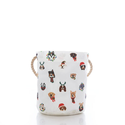 Add a festive touch to your home with the Sea Bags Very Merry Pups Bucket Bag—a white fabric storage basket featuring rope handles and playful illustrations of dogs in holiday accessories on a crisp white background. This eco-friendly basket makes an ideal gift for any dog lover, or a delightful addition to your seasonal décor. by Sea Bags