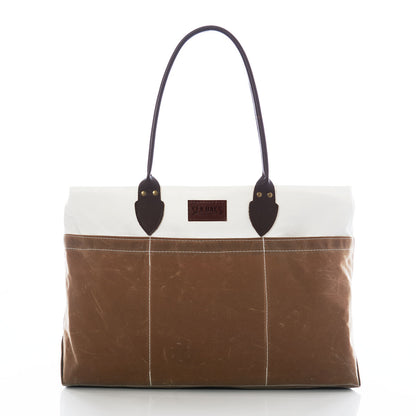 Tan Chebeague Large Travel Tote by Sea Bags, made from recycled sail cloth in brown and white tones, features dark handles, stitched vertical lines, and a rectangular front label, photographed on a white background. by Sea Bags