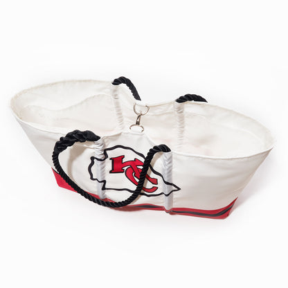 The Kansas City Chiefs Tailgate Tote by Sea Bags is crafted from recycled sail cloth in bold white and red, accented with black rope handles and a metal clasp. Showcasing the iconic Kansas City Chiefs logo, this durable bag is photographed against a clean white background—an ideal blend of style and function for any devoted fan. by Sea Bags