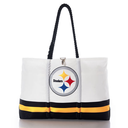 The Sea Bags Pittsburgh Steelers Tailgate Tote, crafted from recycled sail cloth for extra durability, features black handles, the Pittsburgh Steelers logo, and black and yellow stripes near the bottom; this distinctive bag is shown on a reflective surface. by Sea Bags