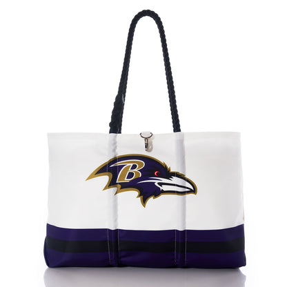 The Baltimore Ravens Tailgate Tote by Sea Bags features a white design with black handles, the Baltimore Ravens logo, and bold purple and black stripes near the bottom. Crafted from recycled sail cloth for enhanced durability, this stylish tote is ideal for both game days and everyday use. by Sea Bags