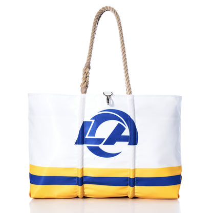 The Los Angeles Rams Tailgate Tote by Sea Bags features yellow and blue stripes, rope handles, and an LA logo on the front. Crafted from recycled sail cloth, this white tote bag is perfect for tailgating, as shown in the product photo set against a white background. by Sea Bags
