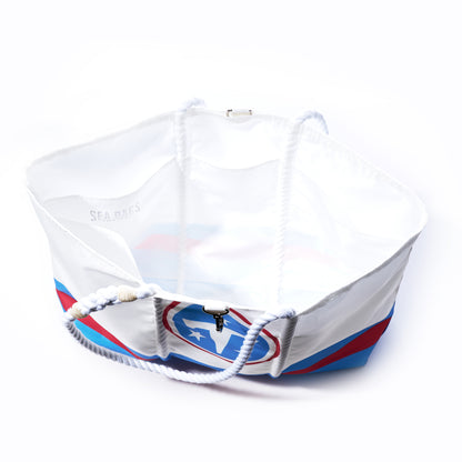 The Tennessee Titans Tailgate Tote by Sea Bags is a large white recycled sail cloth bag featuring navy rope handles and a bold blue, red, and black design on the side. Shown from above to highlight its spacious, empty interior, this tote is the perfect game day accessory. by Sea Bags