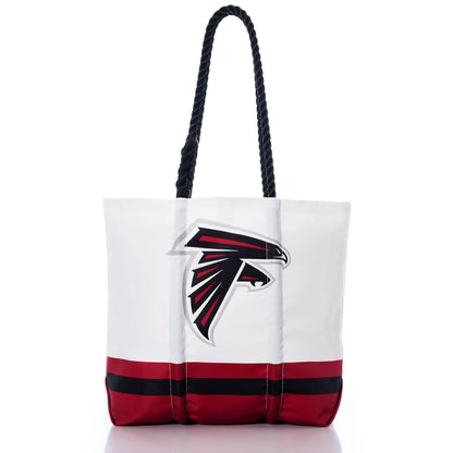 Introducing the Atlanta Falcons Medium Tote by Sea Bags—a white tote featuring black rope handles and striking red and black stripes along the bottom. The front showcases a bold black and red falcon head logo, making it the perfect accessory for any fan. Expertly crafted from recycled sail cloth, this eco-friendly tote combines style with team pride for every outing. by Sea Bags