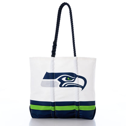 The Sea Bags Seattle Seahawks Medium Tote is crafted from white recycled sail cloth with dark blue handles, featuring the Seattle Seahawks logo along with green and blue stripes near the bottom. Shown on a white background, this stylish tote bag is perfect for any fan. by Sea Bags