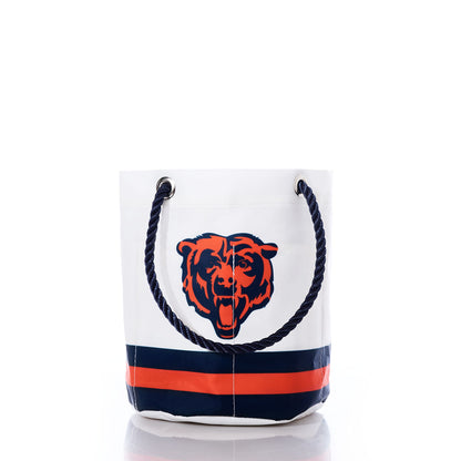 The Sea Bags Chicago Bears Beverage Bucket is a white recycled sail cloth bucket bag with blue rope handles, adorned with a roaring bear logo and horizontal navy and orange stripes near the base—making it the perfect sustainable cooler for showcasing your Chicago Bears pride. by Sea Bags