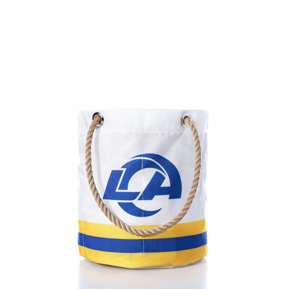 Introducing the Los Angeles Rams Beverage Bucket by Sea Bags—a white sail cloth bag with sturdy rope handles, showcasing a bold blue and yellow Rams logo on the front along with two matching horizontal stripes near the base. Crafted from durable sail cloth, this versatile bag serves as both a sustainable cooler and a stylish beverage bucket, perfect for any occasion. by Sea Bags