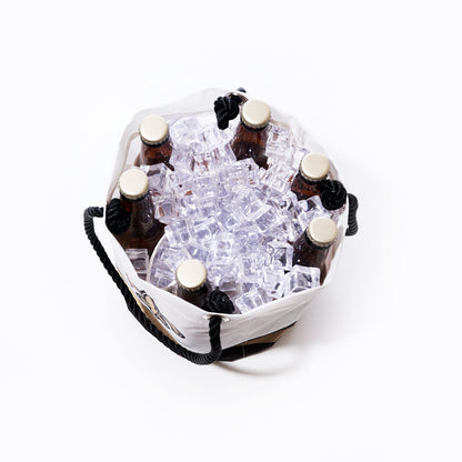 Six brown glass bottles with gold caps are placed upright in a Sea Bags New Orleans Saints Beverage Bucket filled with clear ice cubes, viewed from above on a white background. by Sea Bags