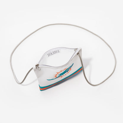 The Sea Bags Miami Dolphins Slim Crossbody is a white pouch crafted from recycled sail cloth, featuring the team’s logo, a silver zipper, and a chain strap—photographed on a white background for fans who value both sustainable design and standout style. by Sea Bags