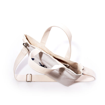 The Navy Anchor Crossbody Tote by Sea Bags, crafted from recycled sailcloth and featuring a zipper closure and two handles, is pictured from above on a white background to reveal its interior pocket. This eco-friendly bag blends practical design with sustainable style. by Sea Bags