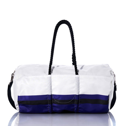 The Baltimore Ravens Duffel by Sea Bags, crafted from recycled sail cloth, features white and blue panels with black rope handles, a detachable shoulder strap, and horizontal color stripes near the base—shown here on a reflective surface. by Sea Bags