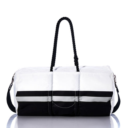A Las Vegas Raiders Duffel by Sea Bags, made from recycled sail cloth, features a two-tone design with a white upper, black base, black side strap, and two black twisted handles, displayed on a reflective surface. by Sea Bags