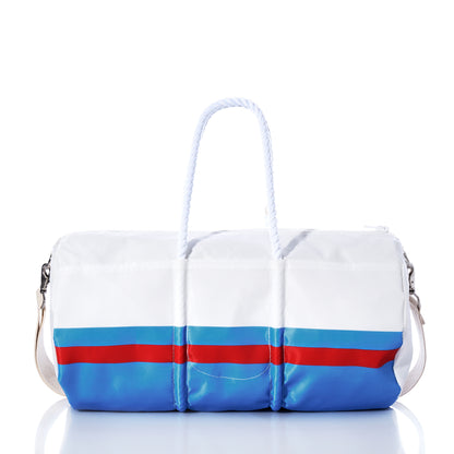 The Tennessee Titans Duffel by Sea Bags is crafted from recycled sail cloth in white and navy blue, featuring a light blue stripe, navy rope handles, and a shoulder strap. The bag is displayed on a reflective surface against a white background. by Sea Bags