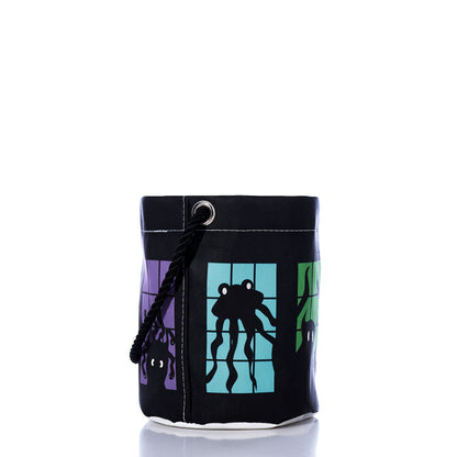 Introducing the Monster Party Bucket Bag from Sea Bags—a black cylindrical bucket bag crafted from recycled sails, featuring a rope handle. Showcasing vibrant square panels adorned with whimsical monster illustrations on a white background, this eco-friendly Halloween accessory brings playful charm to any celebration.