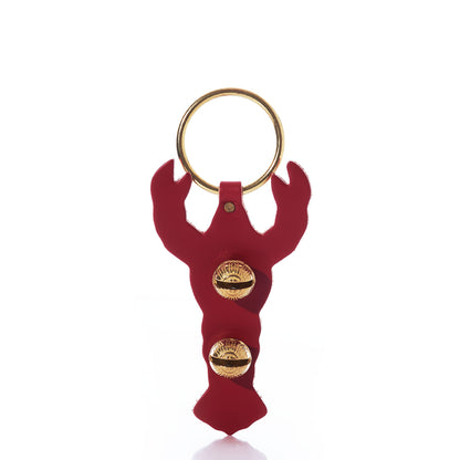 The Red Lobster Door Chime by New England Bells, handcrafted from leather and adorned with two gold seashell accents along with a gold keyring, is showcased against a white background.