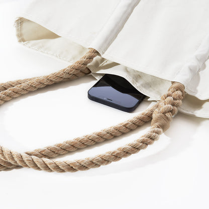A white Mermaid Print Medium Tote by Sea Bags with thick rope handles, shown with a smartphone inside.