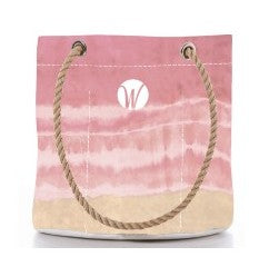 Introducing the Shoreline Blush Essential Handbag by Sea Bags—a pink and beige canvas tote made from sustainable sail cloth. This stylish bag features sturdy rope handles and is accented with a white W logo in a circle on the upper front center. by Sea Bags