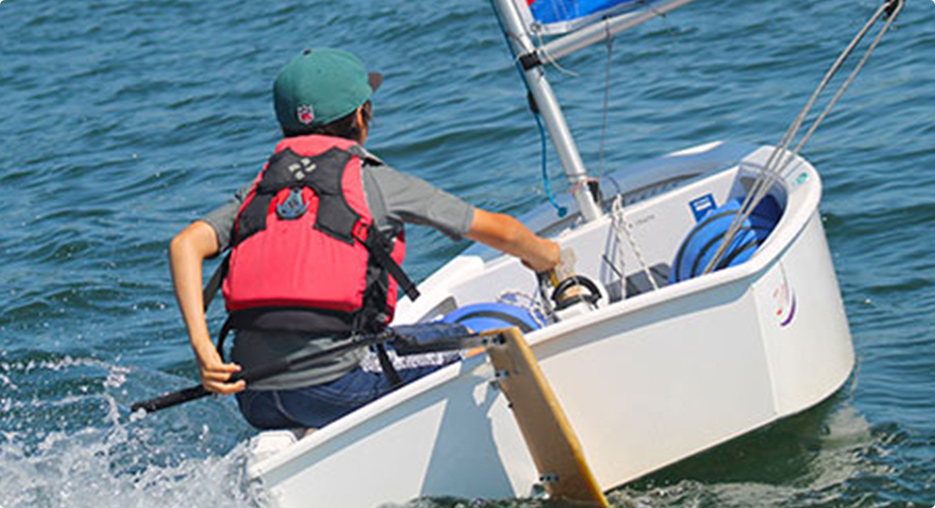Child Steering a Sailboat in the Water