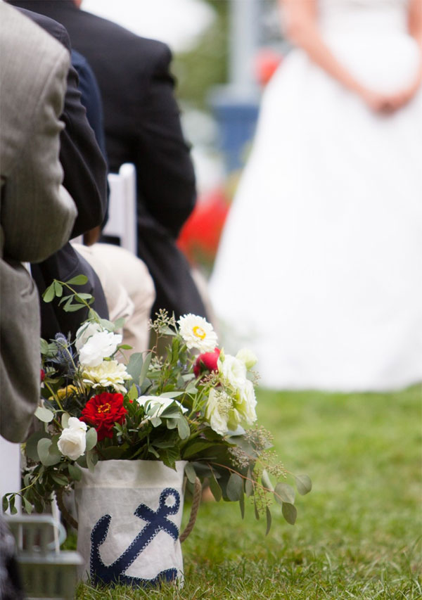 Sea Bags Navy Anchor Bucket Bag is filled with wedding flowers and placed along the aisle for a sustainable wedding decoration.