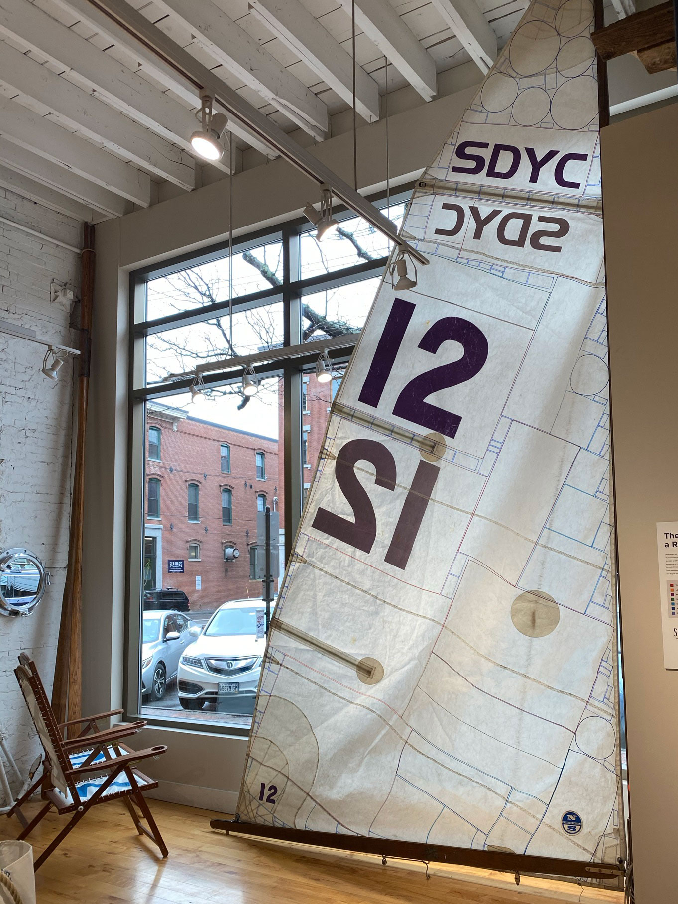 A sail is hanging on a mast in the store, with lines showing how all parts of a sail are salvaged