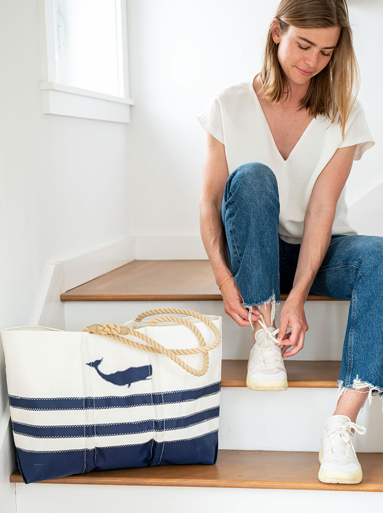 Woman sitting on stairs next to Breton Stripe Whale Ogunquit Beach Tote