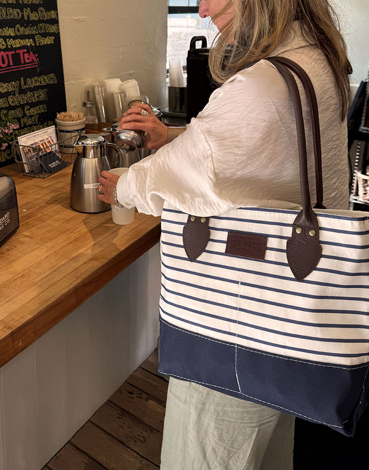 Woman wearing NEW Navy Stripe Chebeague Handbag at a coffee shop