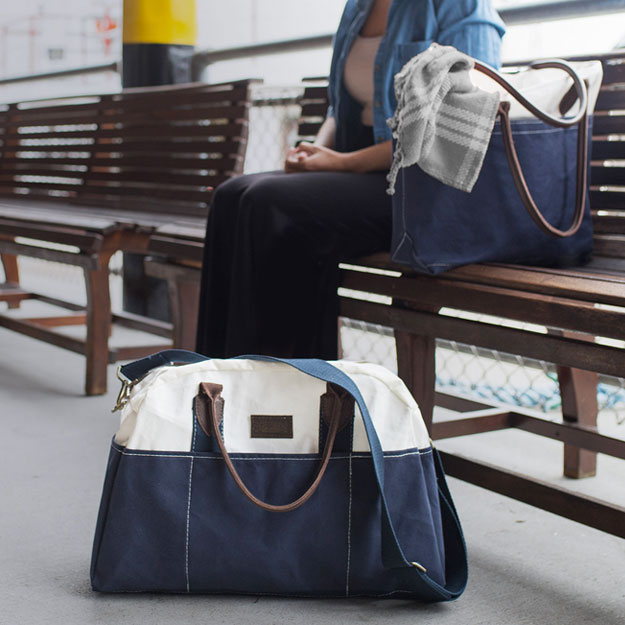 Woman sitting on train bench with Chebeague Weekender and Tote