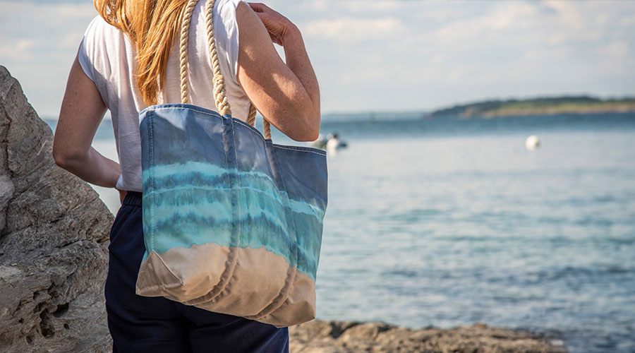 Woman wearing Shoreline Tie Dye Tote over the shoulder on the coast