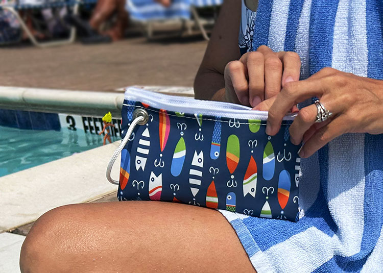 Woman sitting at a pool with Lures Wristlet