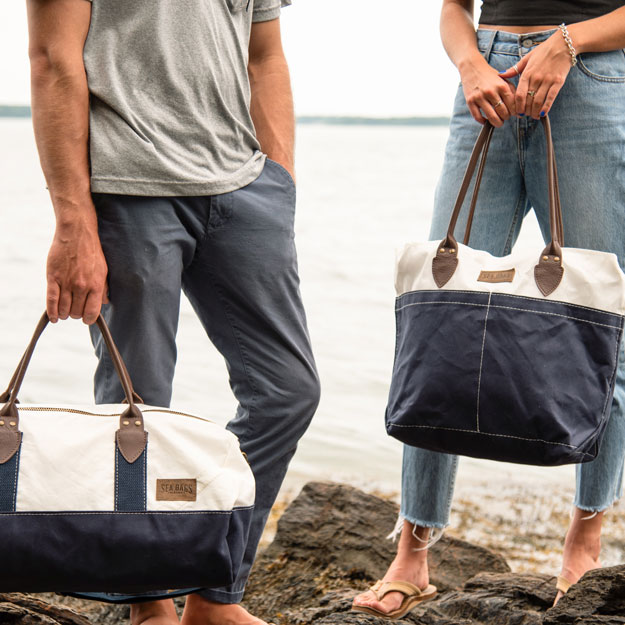 Woman and man on coastline carrying Chebeague Duffel and Tote