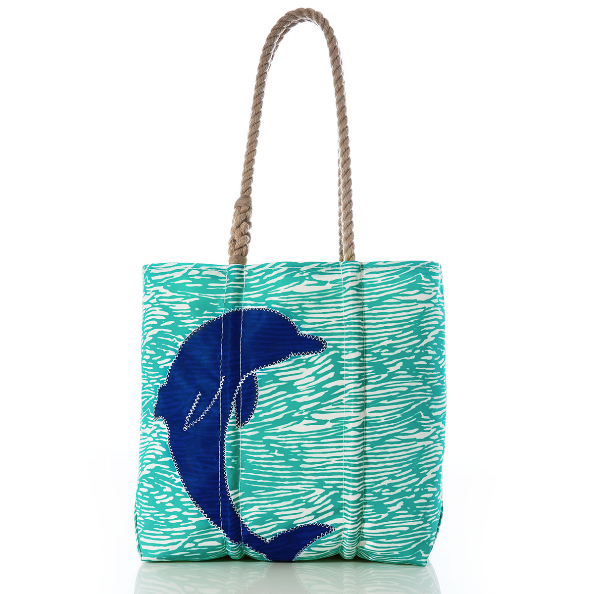 a curved blue dolphin sits on aquamarine waves printed on a recycled sail cloth medium tote with hemp rope handles