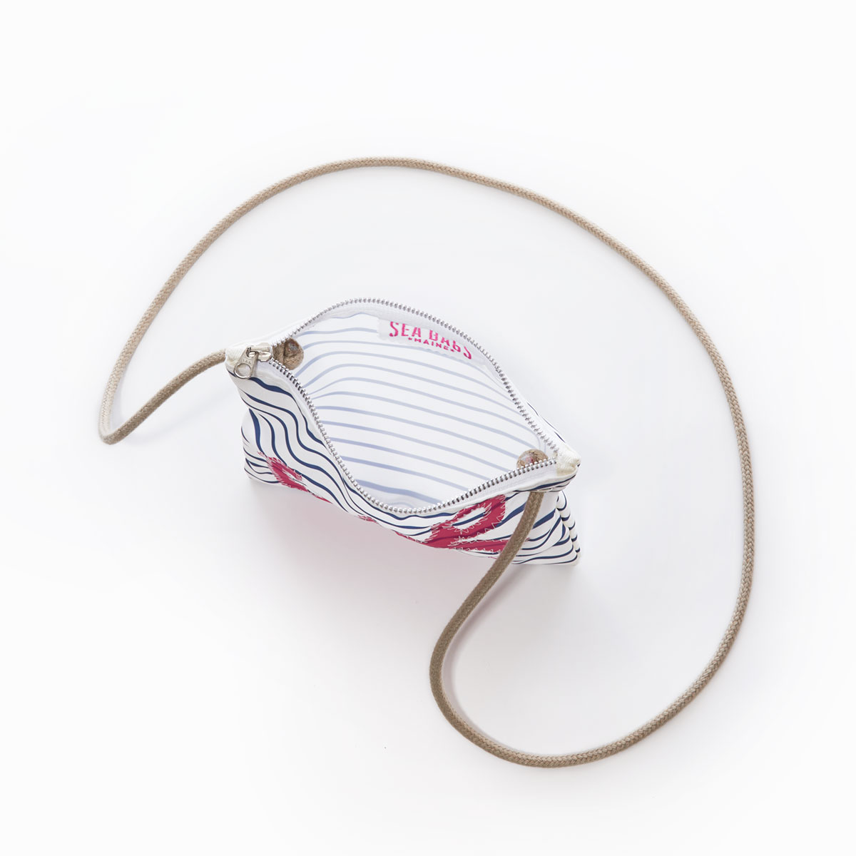 inside view of a recycled sail cloth crossbody with navy and white stripes and a pink anchor and hemp strap