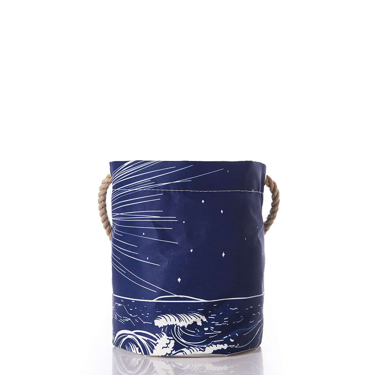 back view: a recycled sail cloth bucket with hemp rope handles is printed with a navy background and a white image of a lighthouse on a coastal rock with waves crashing and the light beaming through the dark