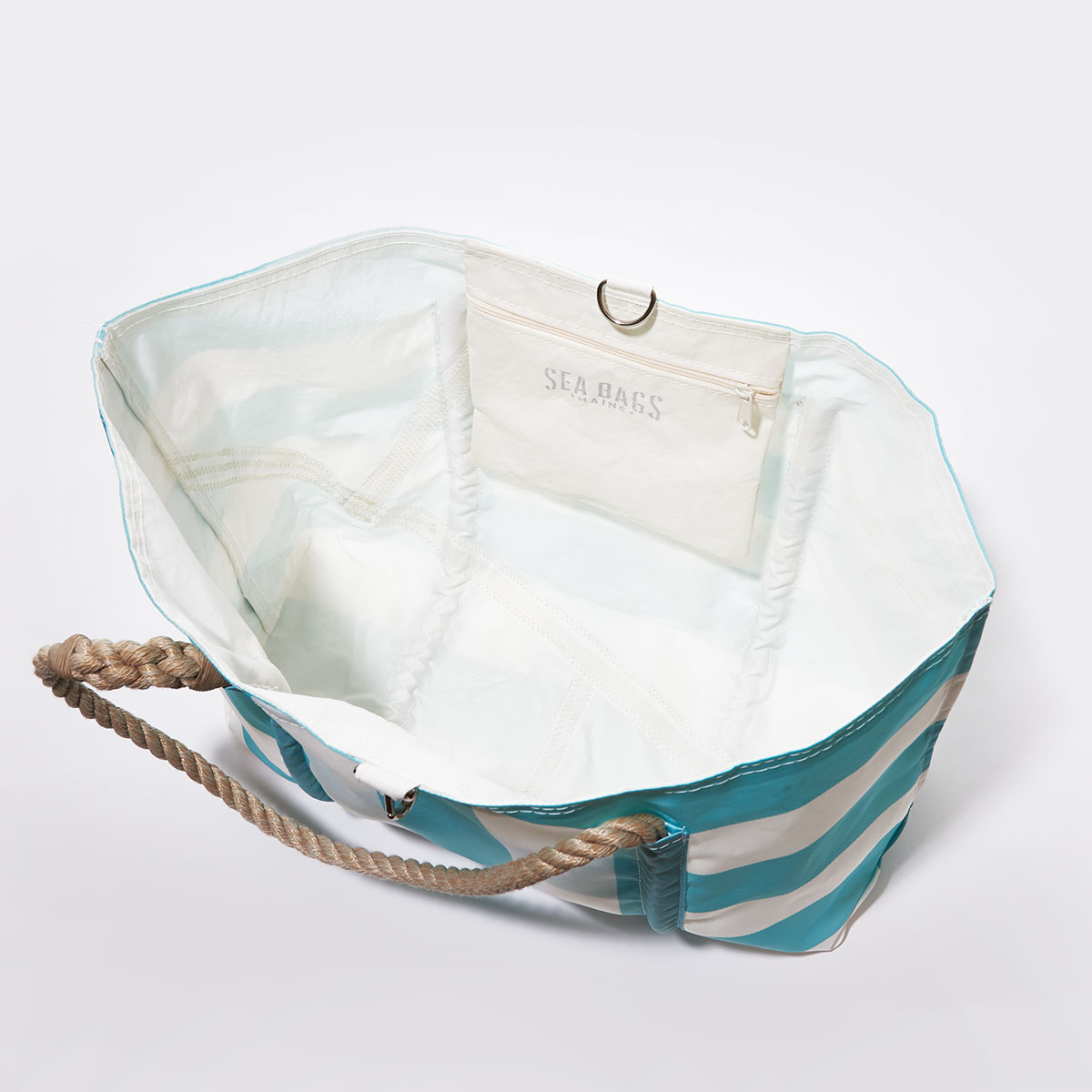inside view: aquamarine and white plaid stripes adorn the front of a recycled sail cloth tote with hemp rope handles and a top metal clasp