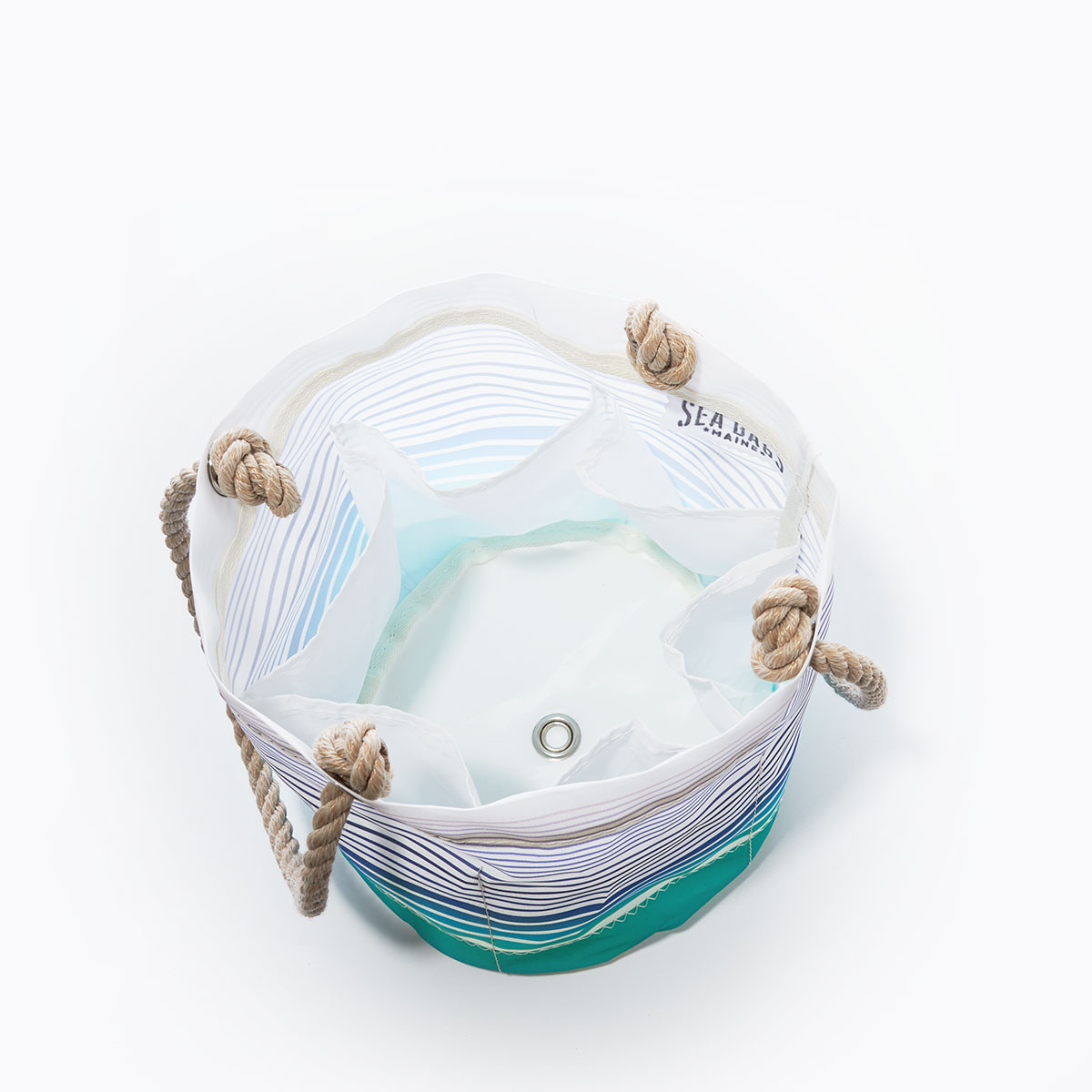 inside view with bottle pockets and bottom grommet of a recycled sail cloth beverage bucket with hemp rope handles is printed with ombre stripes of blue into green with a solid green bottom
