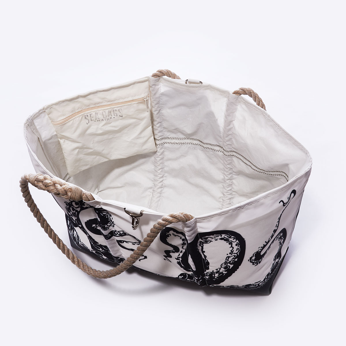 inside view showing interior zippered pocket: black legs of an octopus reach up to the top of this recycled sail cloth tote, with a solid black along the bottom, and hemp rope handles