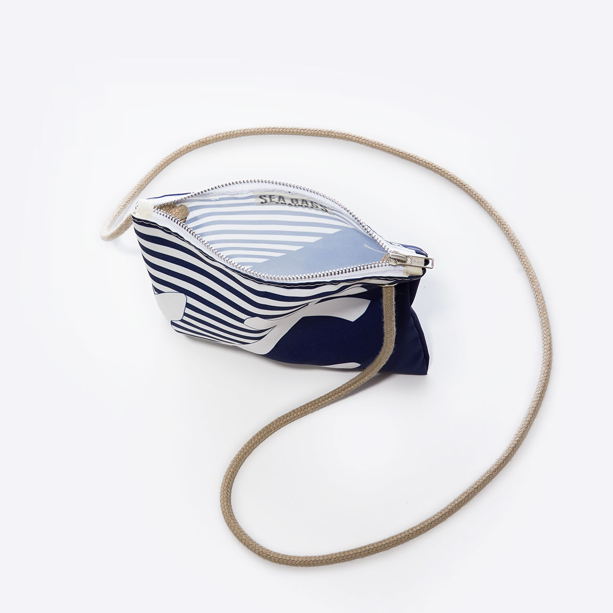 inside view of a a white anchor divides a solid navy blue bottom right triangle and a navy and white striped top left triangle, printed on a recycled sail cloth crossbody bag with tan rope handle
