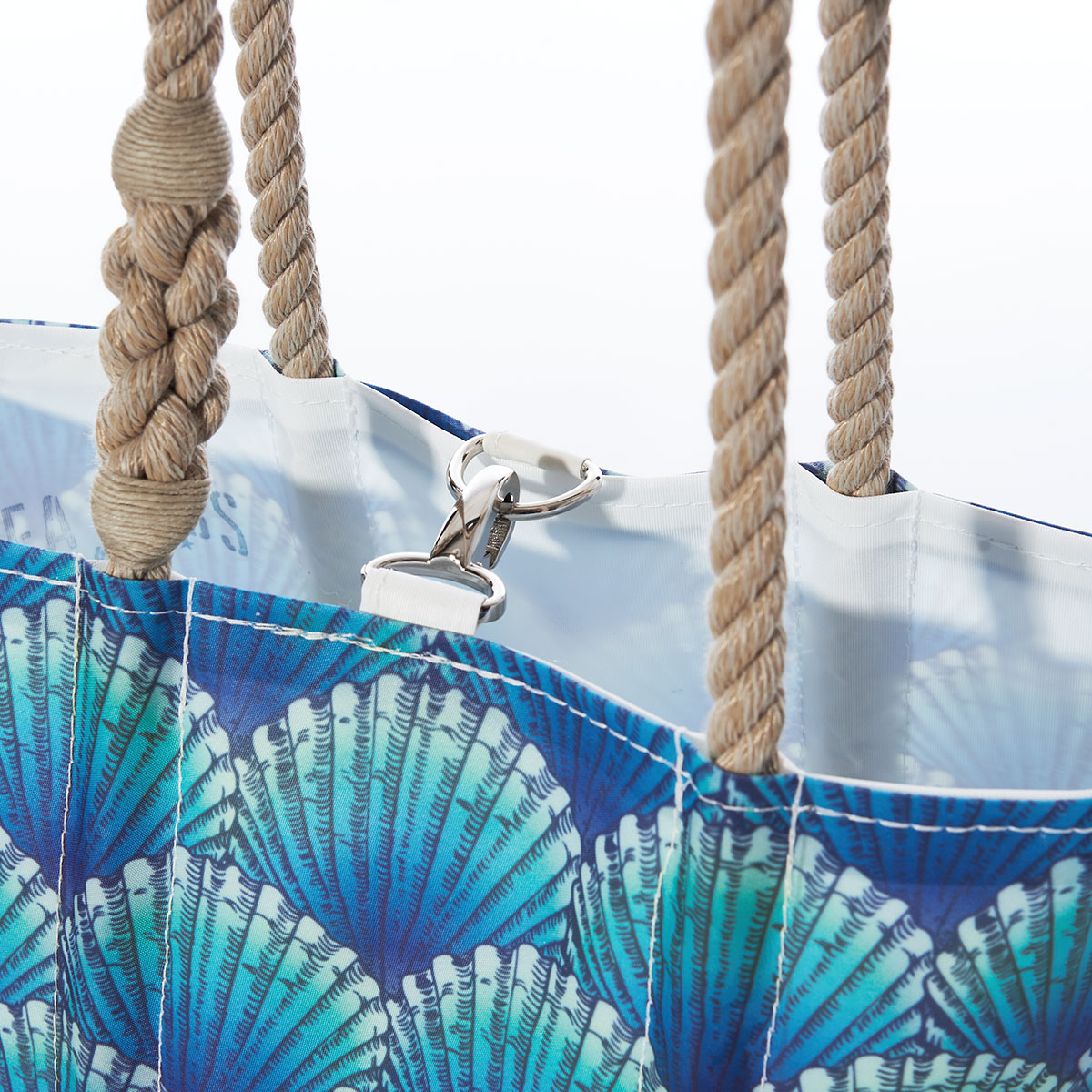 close up of clasp closure on a recycled sail cloth handbag with hemp rope handles is printed with a repeating pattern of blue scallop shells