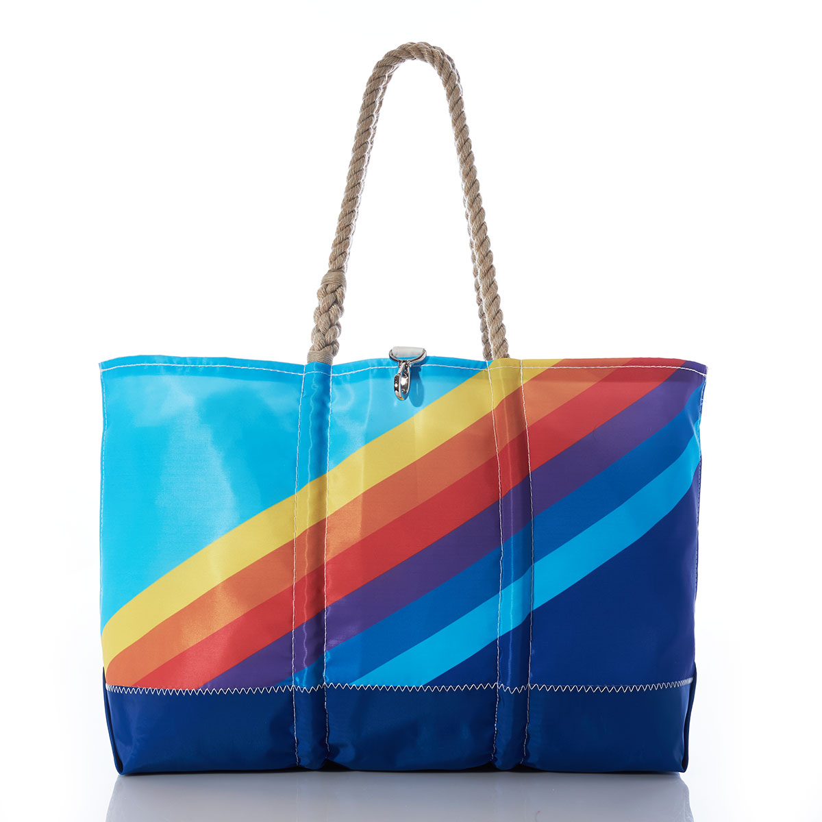 front view of a recycled sail cloth ogunquit beach tote which is printed with retro stripes that range from light blue in the top left corner to dark blue in the bottom right corner, with rainbow colored stripes in between