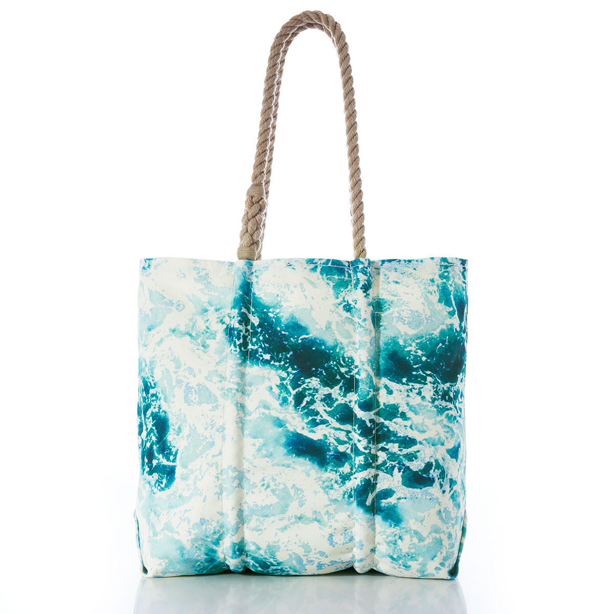 a recycled sail cloth tote with hemp rope handles is printed with a scene of crashing waves upon a shore in bright shades of blue