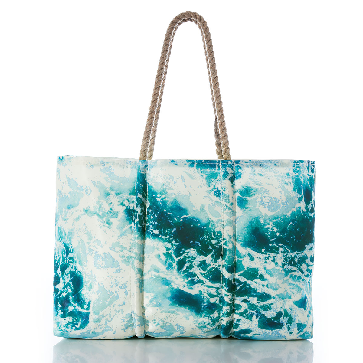 a recycled sail cloth tote with hemp rope handles is printed with a scene of crashing waves upon a shore in bright shades of blue