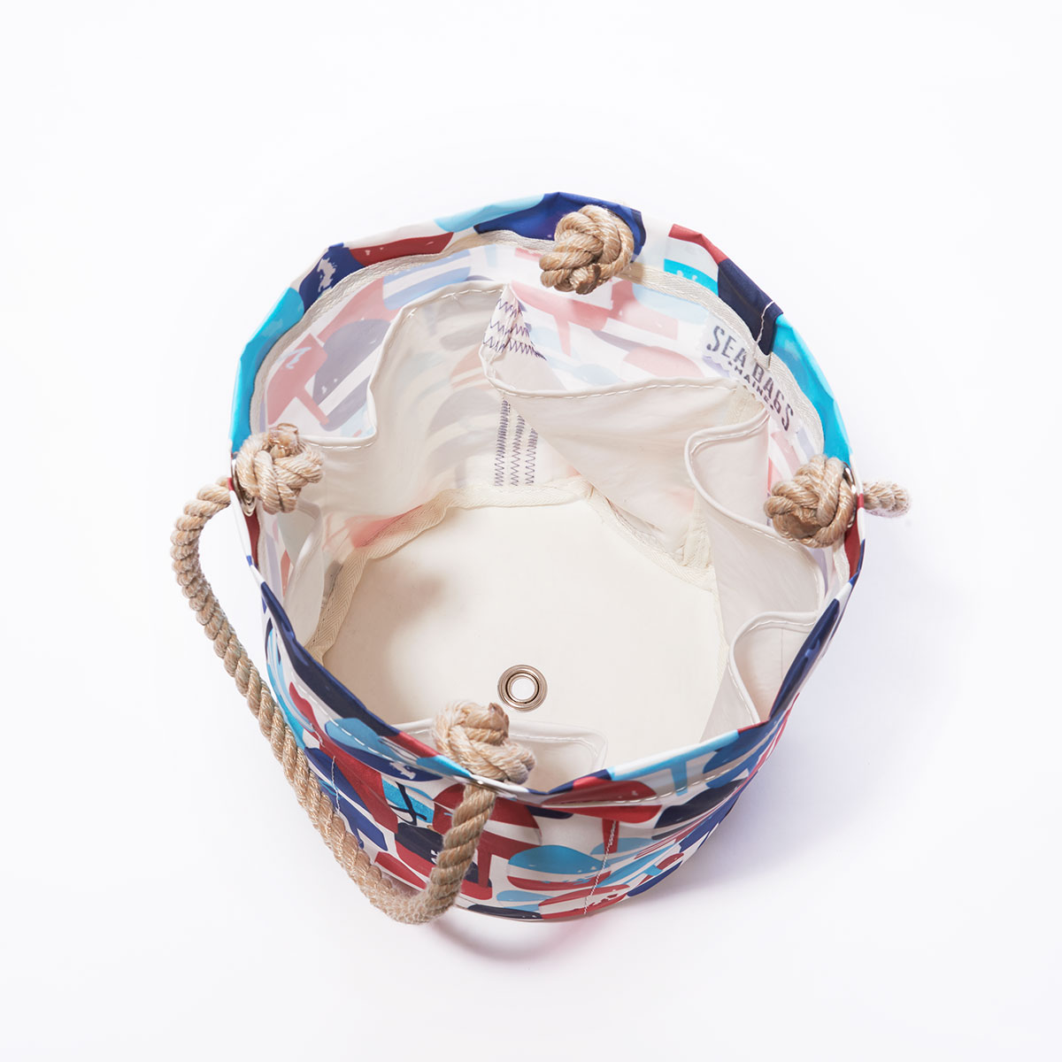 inside view of bottle pockets: a recycled sail cloth beverage bucket bag with hemp rope handles is emblazoned with a variety of printed buoys in reds and blues in different shapes and sizes