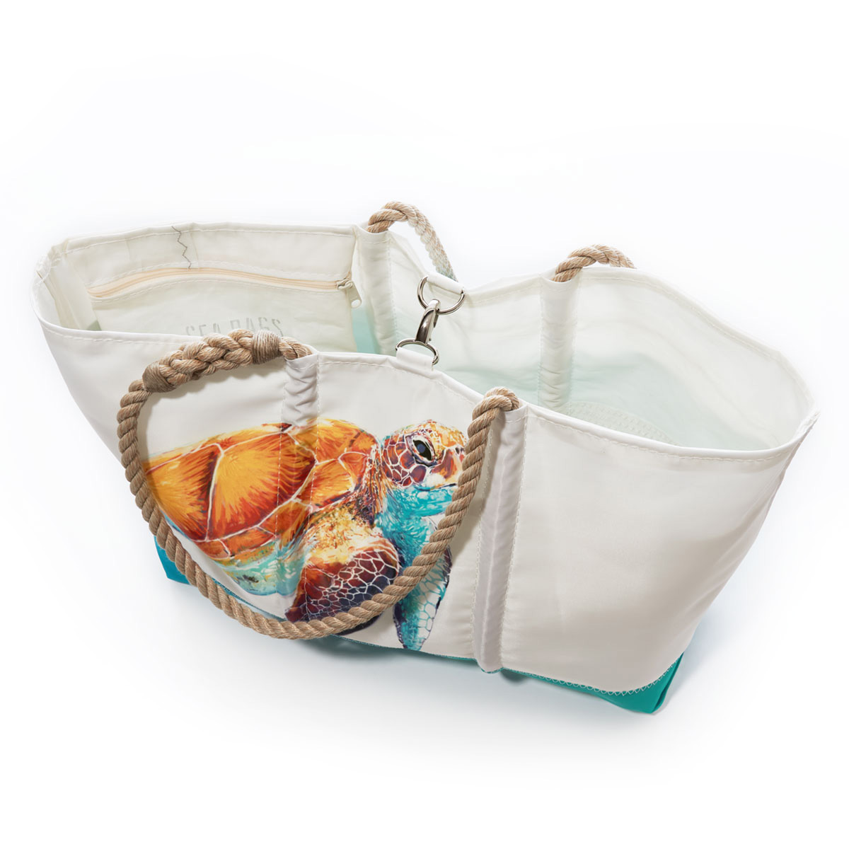 clasp closure of a white recycled sail cloth beach tote with hemp rope handles and a teal wraparound back pocket is printed with a bright friendly multicolor sea turtle