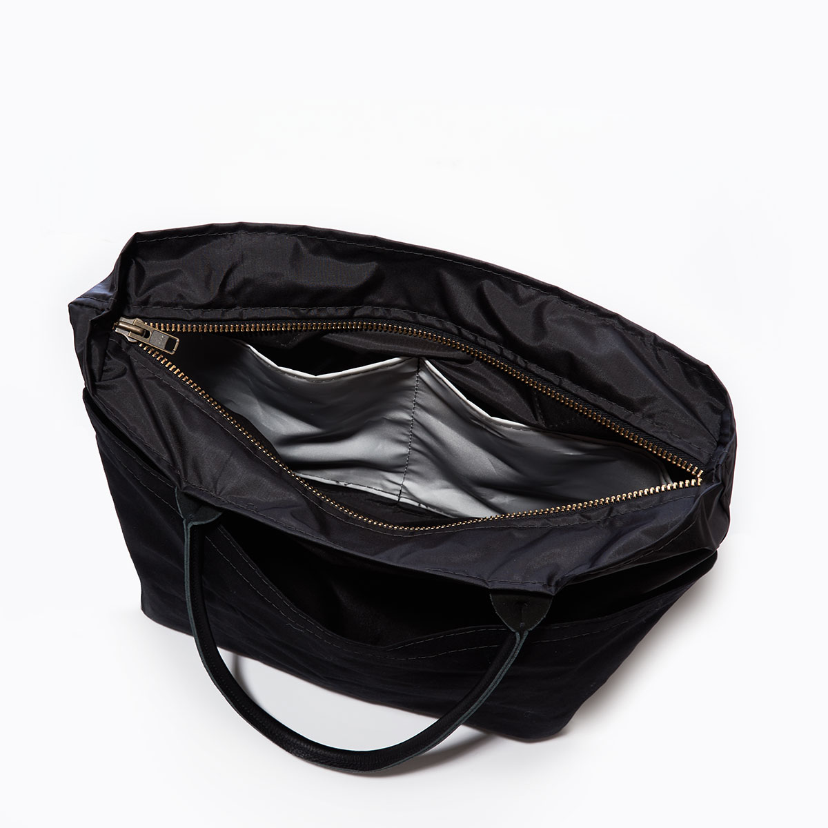 inside view showing interior side pockets of a black recycled sail cloth medium tote with a black canvas bottom and leather handles