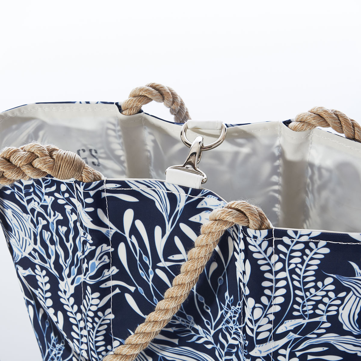 clasp closure on handbag with little fish swim among various types of seaweed in shades of navy and white on a recycled sail cloth handbag with hemp rope handles
