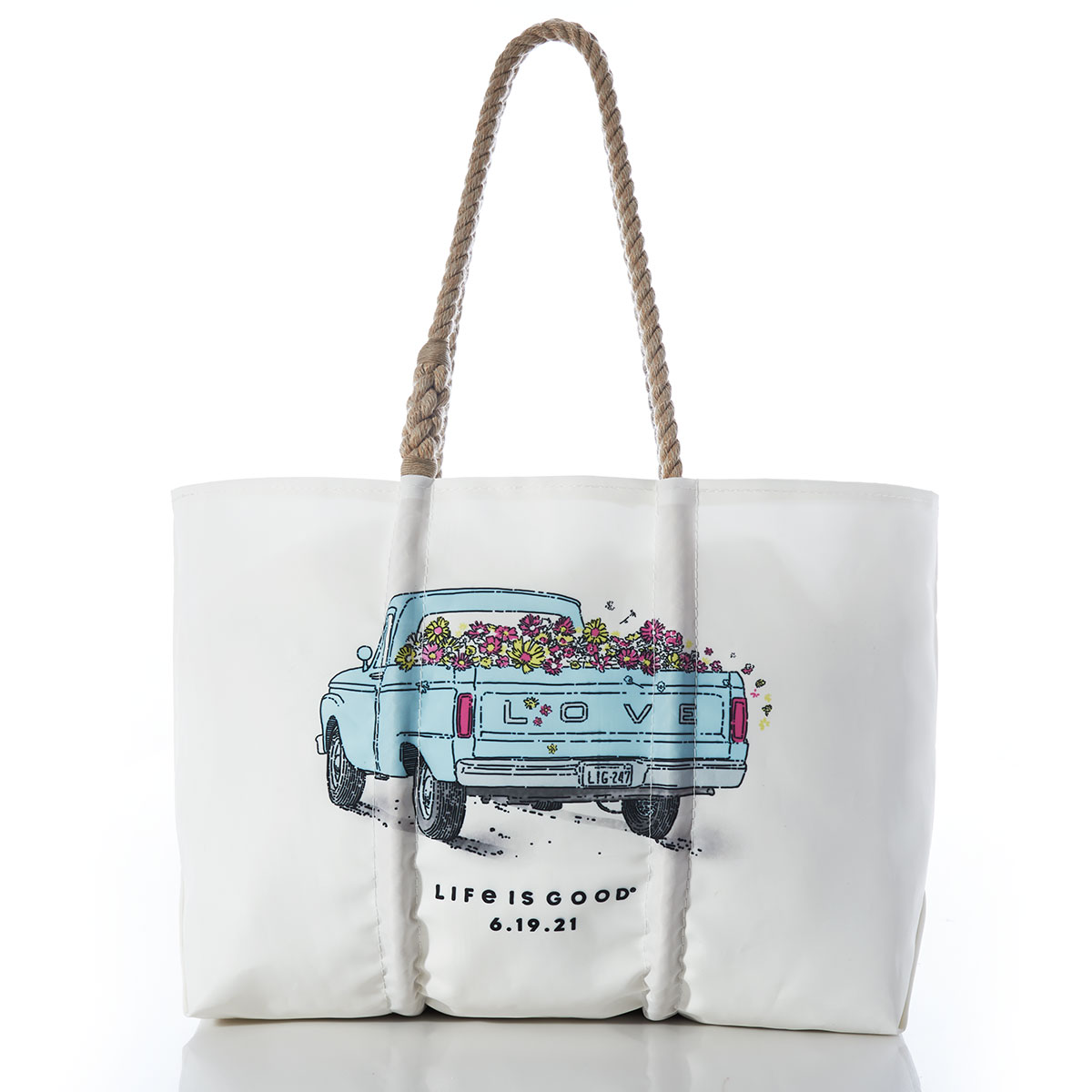 a white recycled sail cloth tote with hemp rope handles is printed with a classic baby blue pick-up truck overflowing with a bed of flowers and LOVE emblazoned on the tail. a customizable date and the life is good brand name sit below the truck