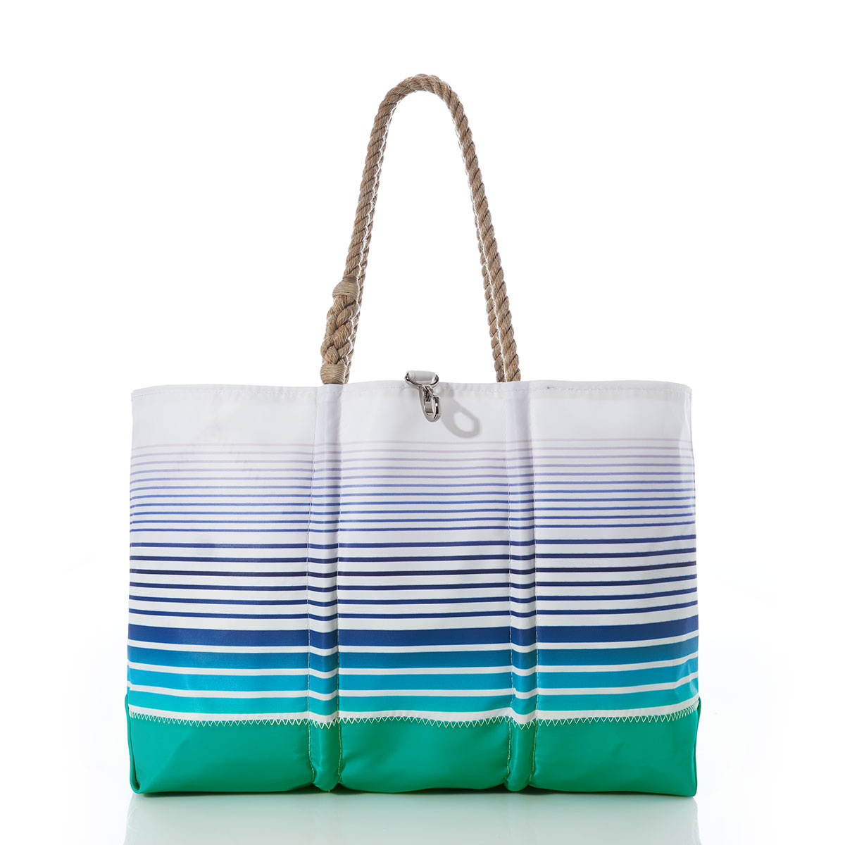 a recycled sail cloth beach tote with hemp rope handles is printed with ombre stripes of blue into green with a solid green bottom