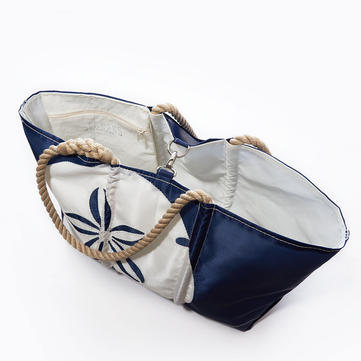 clasp closure of a navy recycled sail cloth ogunquit beach bag with hemp rope handles is embellished with a white sand dollar